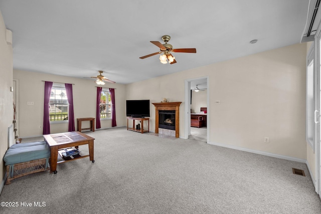 living area featuring a ceiling fan, light carpet, a fireplace with flush hearth, and baseboards