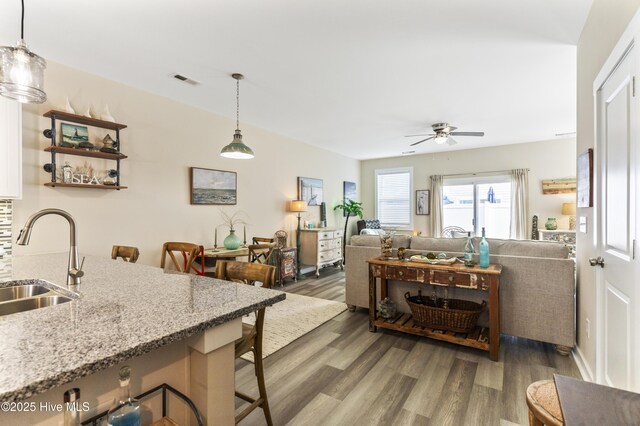 326 Starfish Ln, Sneads Ferry, NC 28460 - kitchen featuring wood finished floors, a sink, a kitchen breakfast bar, ceiling fan, and light stone counters