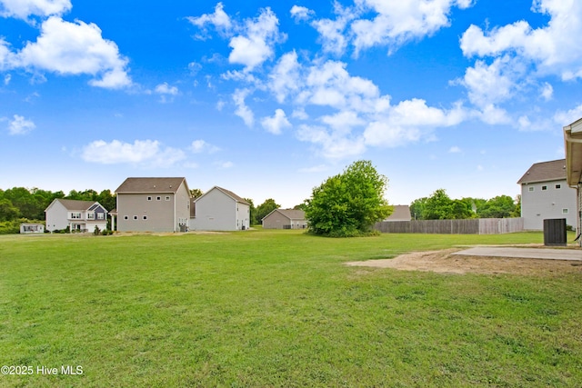 view of yard with cooling unit, fence, and a residential view