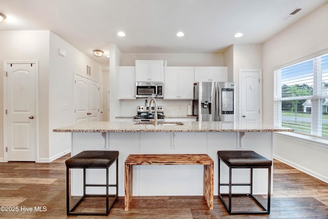 kitchen featuring light stone counters, a breakfast bar area, and appliances with stainless steel finishes
