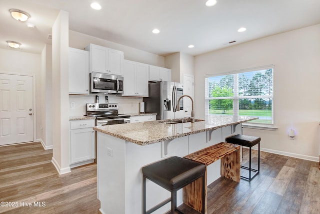 kitchen featuring light wood-type flooring, stainless steel appliances, a kitchen bar, and a sink