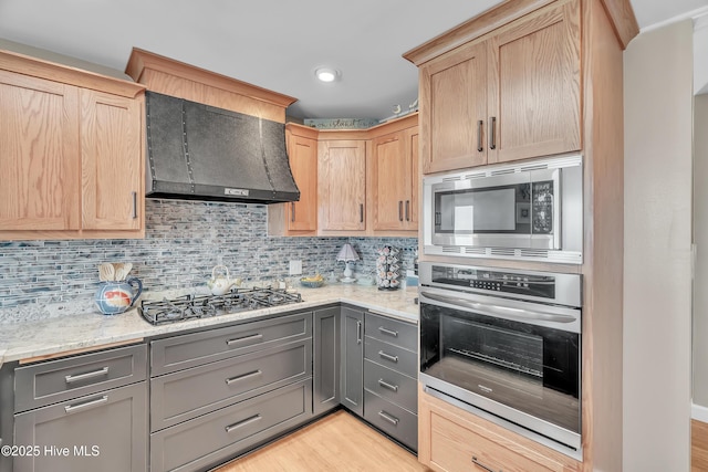 515 Blue Heron Dr, Newport, NC 28570 - kitchen featuring appliances with stainless steel finishes, light brown cabinetry, wall chimney range hood, decorative backsplash, and gray cabinetry