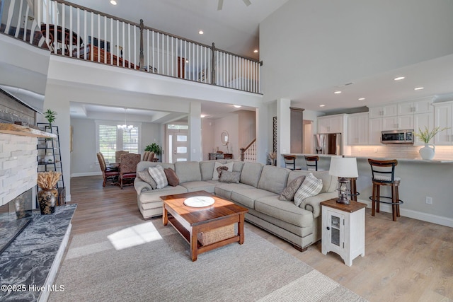 237 Pine Village Dr, Rocky Point, NC 28457 - living room with light wood-type flooring, stairs, a fireplace, a high ceiling, and recessed lighting