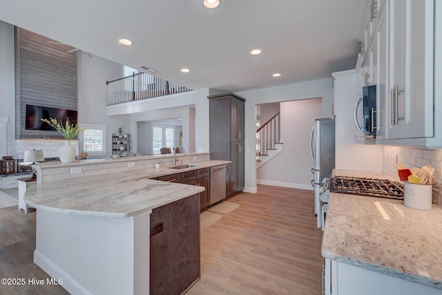 237 Pine Village Dr, Rocky Point, NC 28457 - kitchen featuring stainless steel appliances, decorative backsplash, a peninsula, light wood finished floors, and light stone counters