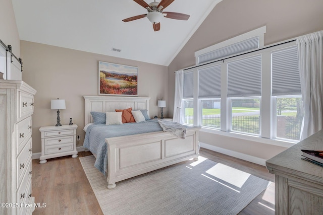 237 Pine Village Dr, Rocky Point, NC 28457 - bedroom featuring a barn door, light wood-style flooring, ceiling fan, and high vaulted ceiling