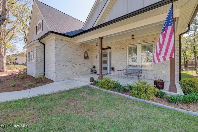 237 Pine Village Dr, Rocky Point, NC 28457 - property entrance with brick siding, covered porch, a shingled roof, and board and batten siding