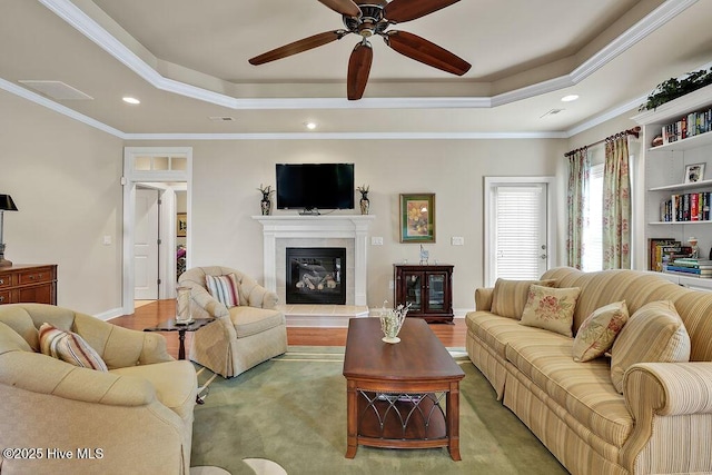 3284 Gardenwood Dr, Leland, NC 28451 - living room featuring a raised ceiling, recessed lighting, crown molding, a ceiling fan, and a glass covered fireplace