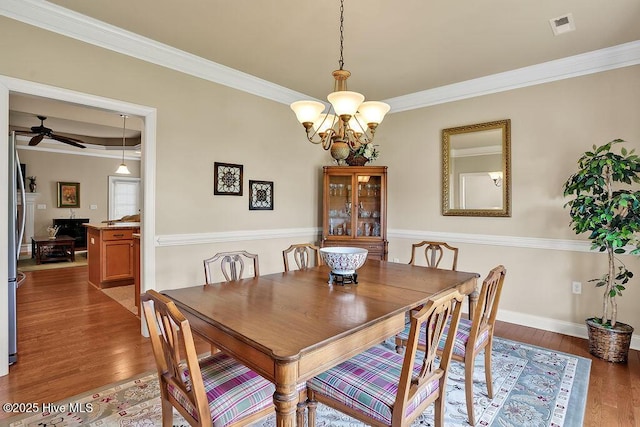 3284 Gardenwood Dr, Leland, NC 28451 - dining space featuring wood finished floors, crown molding, ceiling fan, baseboards, and a chandelier