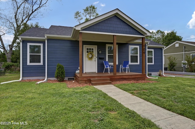 view of front facade with a porch, a front lawn, and a shingled roof