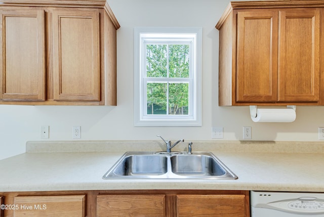 kitchen featuring brown cabinets, light countertops, a sink, and dishwasher