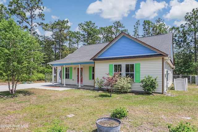 view of front of property featuring a front lawn, roof with shingles, covered porch, and fence