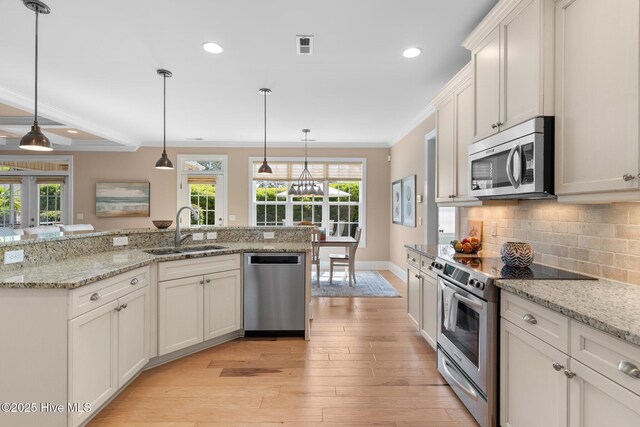 kitchen with stainless steel appliances, a sink, ornamental molding, healthy amount of natural light, and tasteful backsplash