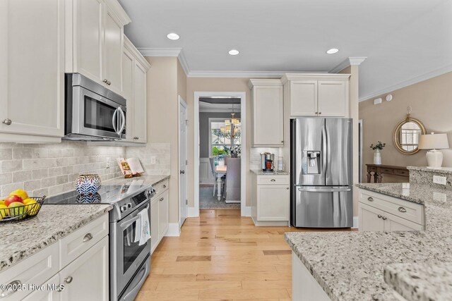kitchen with appliances with stainless steel finishes, crown molding, light wood-style floors, white cabinets, and tasteful backsplash
