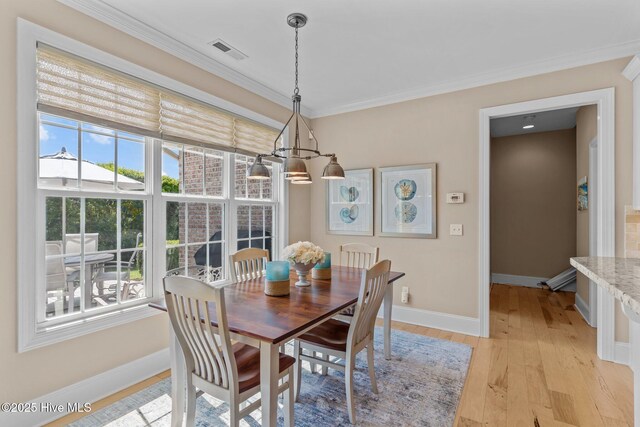 dining space featuring plenty of natural light, light wood-style flooring, baseboards, crown molding, and a chandelier