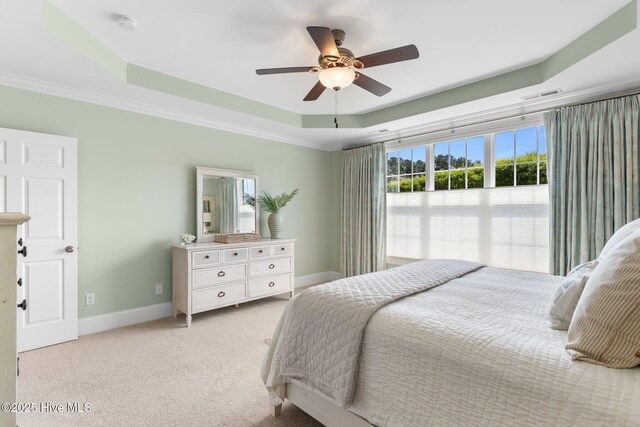bedroom featuring a raised ceiling, baseboards, light colored carpet, a ceiling fan, and ornamental molding