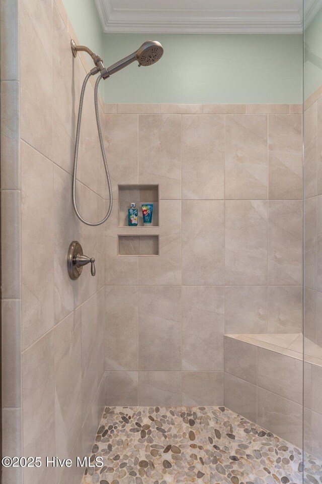 bathroom with a tile shower and ornamental molding