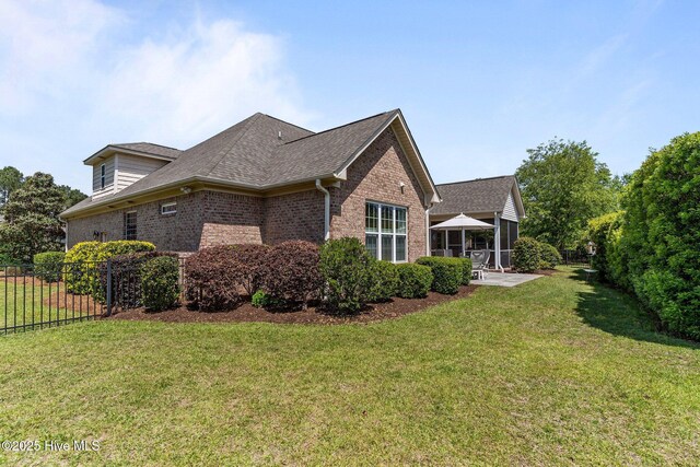 view of side of home with brick siding, a patio area, and roof with shingles