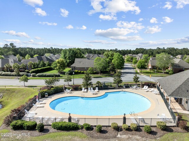 community pool featuring fence, a residential view, and a patio
