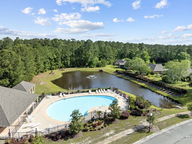 bird's eye view of a pool area, a nearby body of water, and a forest