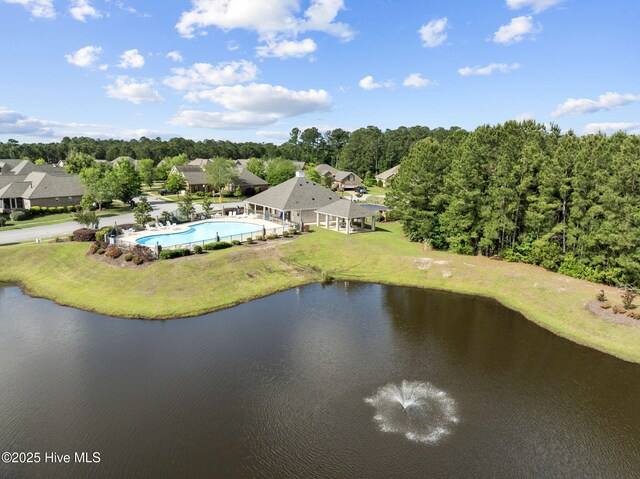 bird's eye view of a pool, a large body of water, and a tree filled landscape