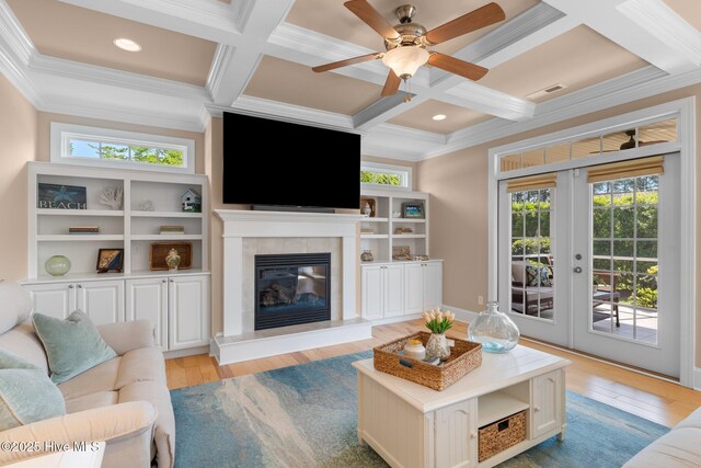 living area featuring coffered ceiling, healthy amount of natural light, crown molding, french doors, and beam ceiling