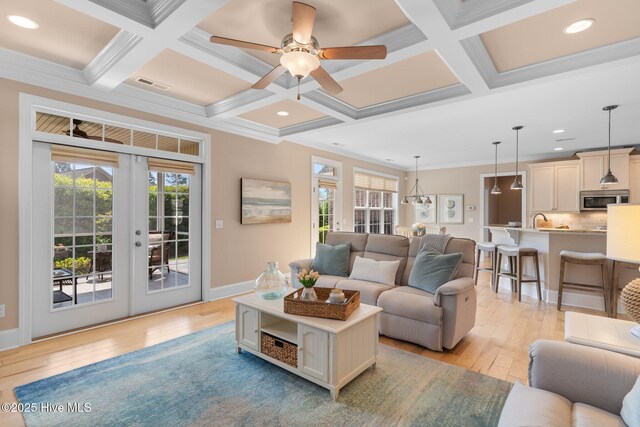 living room with coffered ceiling, light wood-type flooring, french doors, a ceiling fan, and beam ceiling