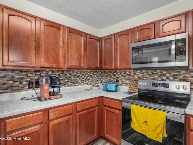 102 Flat Rock Ln, Richlands, NC 28574 - kitchen featuring appliances with stainless steel finishes, backsplash, light stone counters, and brown cabinetry