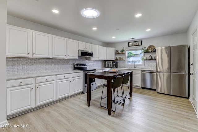 kitchen featuring appliances with stainless steel finishes, open shelves, a sink, white cabinets, and tasteful backsplash