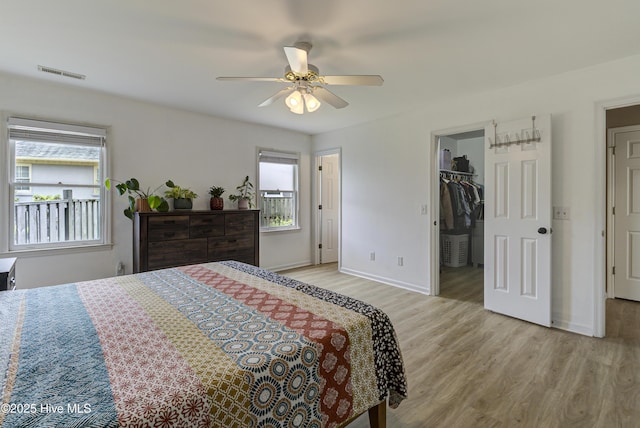bedroom featuring wood finished floors, baseboards, a spacious closet, and ceiling fan