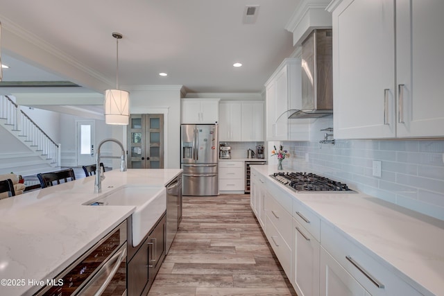 374 Yucca Ln, Wilmington, NC 28412 - kitchen featuring appliances with stainless steel finishes, wall chimney range hood, a sink, wine cooler, and light wood-type flooring