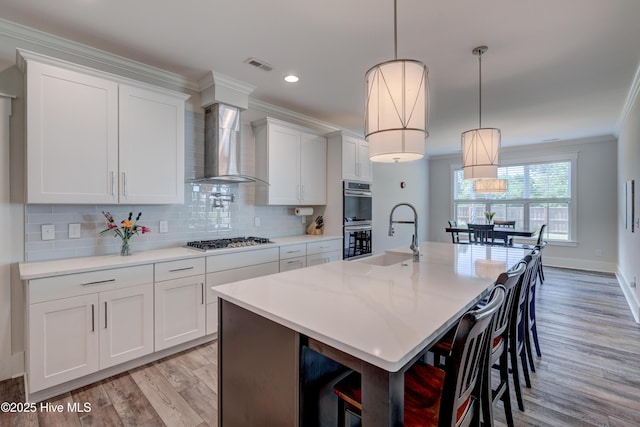 374 Yucca Ln, Wilmington, NC 28412 - kitchen with wall chimney range hood, a sink, stainless steel appliances, light wood-type flooring, and ornamental molding