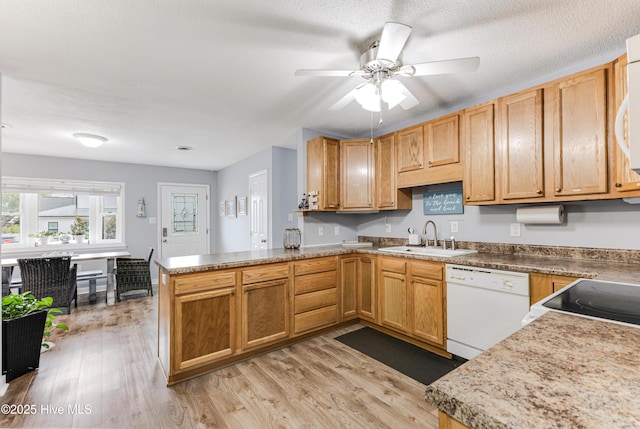 kitchen featuring white appliances, a sink, a peninsula, light wood-style flooring, and a ceiling fan