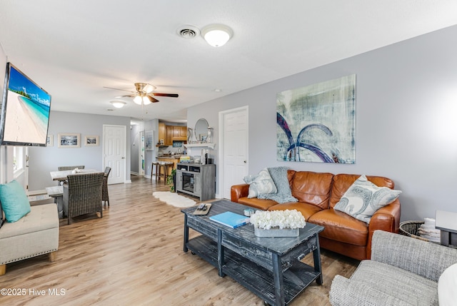 living area featuring light wood-style floors, ceiling fan, and baseboards