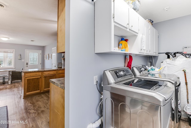 washroom featuring washing machine and dryer, cabinet space, and dark wood finished floors