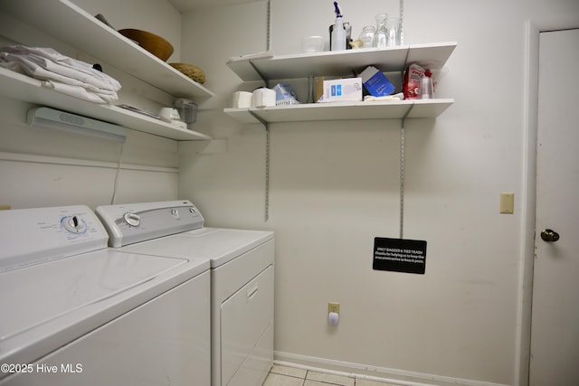 laundry area with washing machine and dryer, light tile patterned flooring, and baseboards