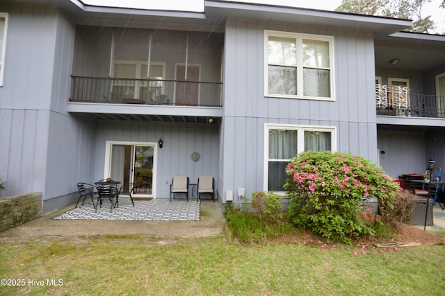 rear view of property featuring a patio area, a balcony, and a yard