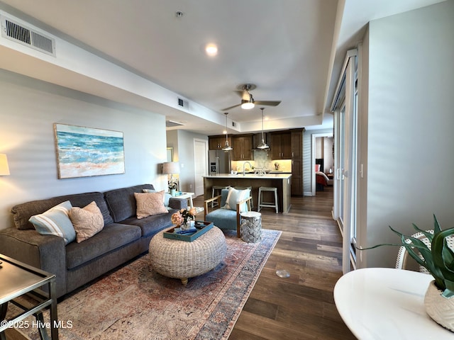 living room with visible vents, ceiling fan, and dark wood-type flooring