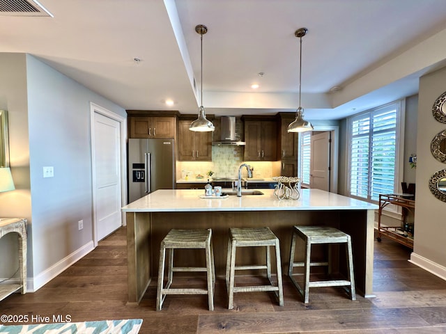 kitchen with a breakfast bar, visible vents, wall chimney exhaust hood, backsplash, and high quality fridge