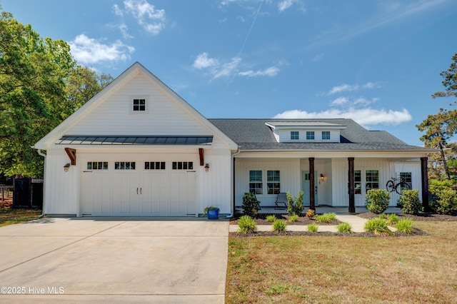 719 Atlanta Ave, Carolina Beach, NC 28428 - modern farmhouse featuring covered porch, an attached garage, a standing seam roof, concrete driveway, and a front yard