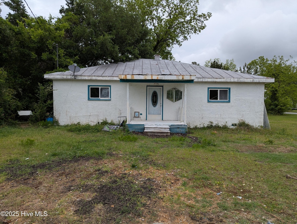 view of front facade with covered porch, stucco siding, and a front yard
