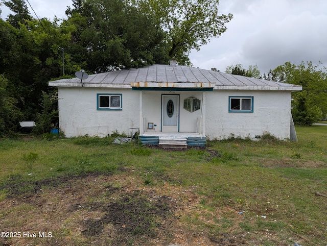 view of front facade with covered porch, stucco siding, and a front yard