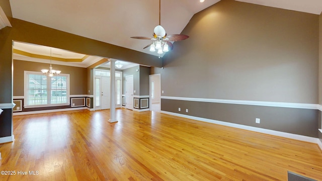 unfurnished living room with ornamental molding, light wood-type flooring, ornate columns, and ceiling fan with notable chandelier