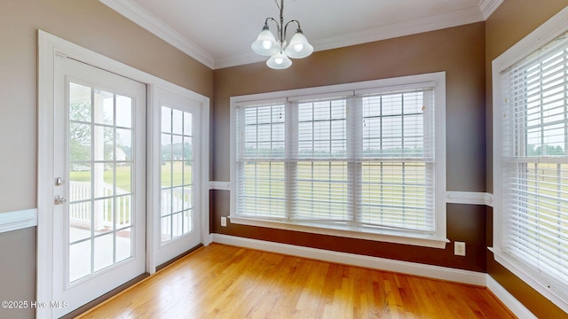 entryway with baseboards, ornamental molding, a chandelier, and light wood-style flooring
