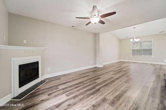 unfurnished living room featuring baseboards, wood finished floors, ceiling fan with notable chandelier, and a glass covered fireplace