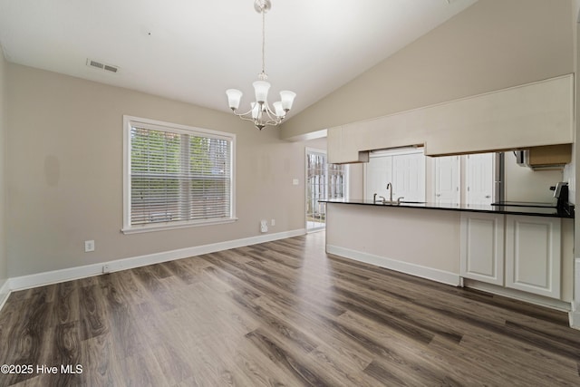 interior space featuring baseboards, a notable chandelier, visible vents, and dark wood-type flooring
