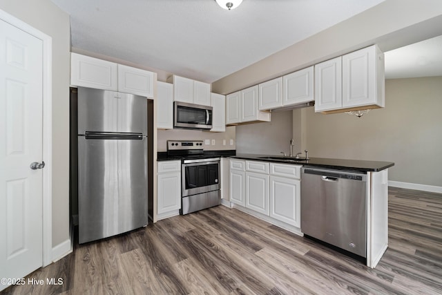 kitchen featuring dark wood-style flooring, dark countertops, appliances with stainless steel finishes, and a sink