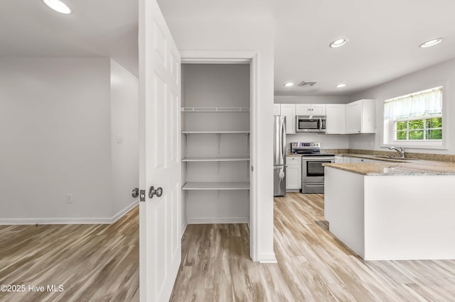 1406 Silverbrook Rd, Oriental, NC 28571 - kitchen with appliances with stainless steel finishes, a sink, light wood-style flooring, white cabinetry, and recessed lighting