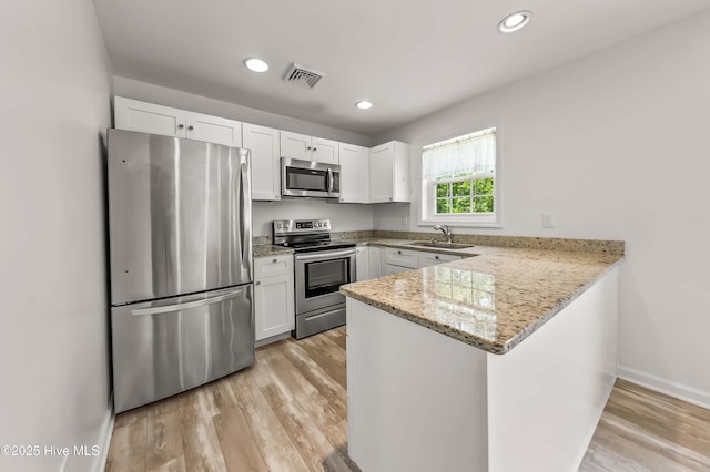 1406 Silverbrook Rd, Oriental, NC 28571 - kitchen with appliances with stainless steel finishes, a peninsula, white cabinetry, a sink, and light wood-type flooring