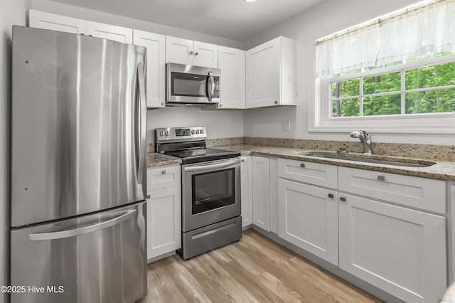 1406 Silverbrook Rd, Oriental, NC 28571 - kitchen with appliances with stainless steel finishes, a sink, white cabinetry, and light wood-style flooring