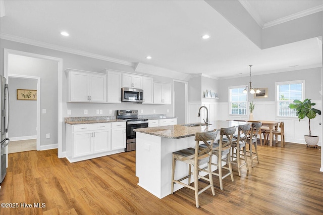 kitchen featuring light stone countertops, white cabinets, appliances with stainless steel finishes, and a sink